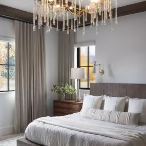 Achieve ultimate comfort and style with custom drapery from GrandView Blinds & Designs. This luxurious bedroom features floor-length panels offering superior light control and privacy, complementing the sophisticated rustic-modern decor.