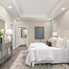 A large bedroom with plush carpet, a window, recessed lighting, and access to a private bathroom.