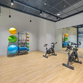 Modern fitness studio with cycling equipment, strength training accessories, and a mirrored wall.