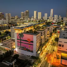 Vibrant aerial view of a modern apartment community in the heart of Wynwood, surrounded by city lights and artistic murals.