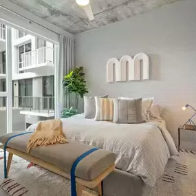 Stylish bedroom with floor-to-ceiling windows, textured accent wall, and modern decor.