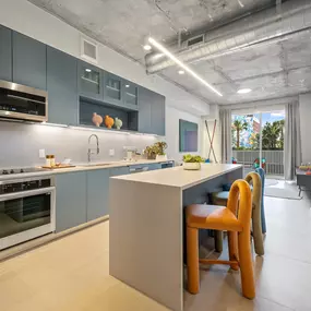 A fully equipped, modern kitchen featuring stainless steel appliances, an island with seating, and ample storage space.