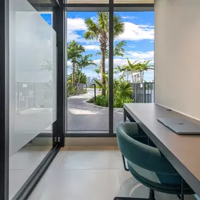 A well-lit, dedicated co-working space with a clean and modern desk, complete with a comfortable chair and a view of the outdoor area.