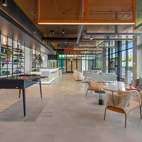 A stylish and modern community lounge with comfortable seating, a foosball table, and an inviting atmosphere perfect for socializing.