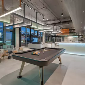 his upscale game room includes a pool table for residents to enjoy friendly matches, surrounded by contemporary furniture.