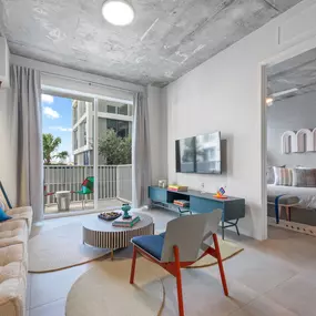 A contemporary living room with a comfortable sofa, colorful accent chairs, and a sleek TV unit.