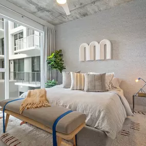 A chic bedroom featuring soft neutral tones, plush bedding, and large windows that offer ample natural light. T