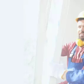 Das Bild zeigt zwei Handwerker in Arbeitskleidung, die gemeinsam ein Fenster installieren. Beide Männer tragen Helme und Gehörschutz um den Hals, was auf eine sichere Arbeitsumgebung und professionelle Arbeitsweise hinweist. Der Mann links trägt eine rote Arbeitsjacke und gelben Helm, während der Mann rechts eine blaue Jacke und einen weißen Helm trägt. Das Bild vermittelt Professionalität und Teamarbeit, die für den Service von Fenster Express wichtig sind.