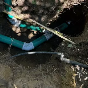 A close-up of a sewer line repair with green pipes being installed in a trench. Knight Rooter ensures effective, long-lasting sewer line repairs using top-quality materials and techniques.