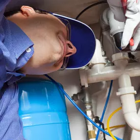 A plumber working on installing a water filter underneath a sink