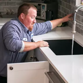 A Done plumber testing a kitchen sink