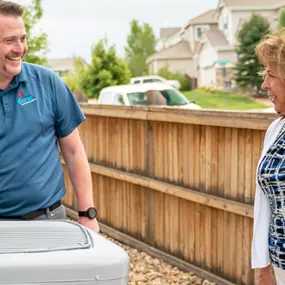 A Done HVAC Technician talking to a customer outside by the AC unit