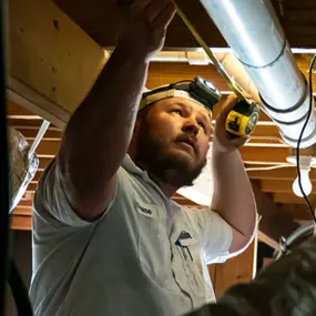 A 72 Degrees Texas technician working on pipes underneath a home