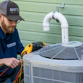 A Mainstream Home Services technician working on an AC unit