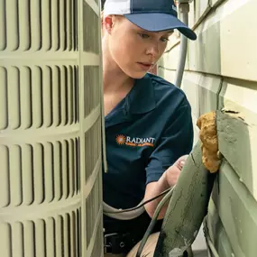 A Radiant San Antonio HVAC technician inspecting an AC unit outside