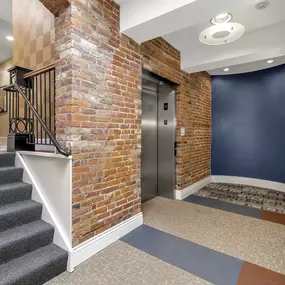 the front door of a building with a brick wall and stairs at The Granite Works Apartments , Buffalo, NY