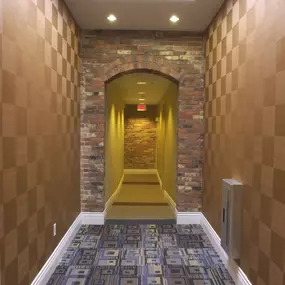 a hallway with a carpeted floor and a brick wall with a ceiling light at The Granite Works Apartments , Buffalo, New York