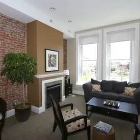 a living room with a brick wall and a couch and a table at The Granite Works Apartments , Buffalo, NY, 14202