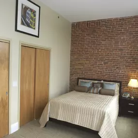 a bedroom with a bed and a brick wall at The Granite Works Apartments , New York