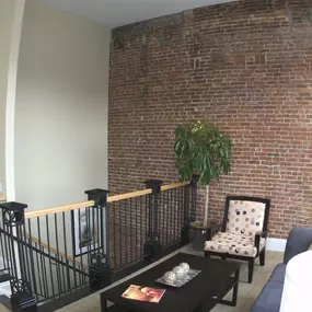 a living room with a brick wall and a couch and a chair at The Granite Works Apartments , New York 14202