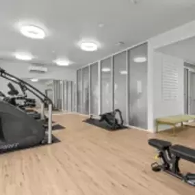 a gym with treadmills and other exercise equipment on a wood floor