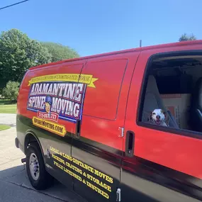 Adamantine Spine Moving van with a dog in the passenger seat.