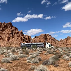 Adamantine Spine Moving truck parked against a stunning desert landscape.