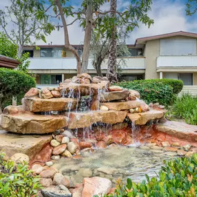 a backyard waterfall with a building in the background