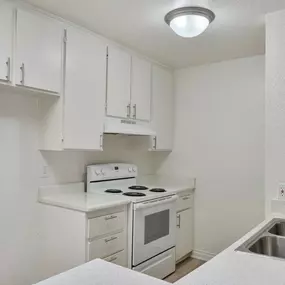 a kitchen with white cabinets and white appliances and a sink
