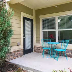 A patio with blue chairs and a table