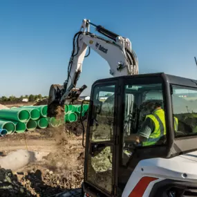 Bobcat Construction Equipment on a construction site moving pieces of material with a large machine with bucket attachment.