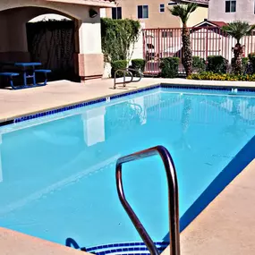 A pool with a ladder in the foreground and a building in the background