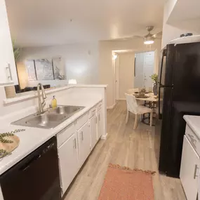 a kitchen and dining room with a black refrigerator and sink