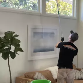 Technician expertly cleaning a high ceiling affected by smoke damage.