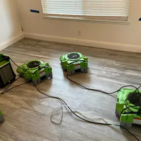 Using professional air movers and a dehumidifier to dry a water-damaged room.