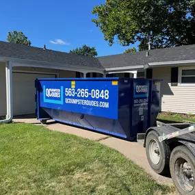 A QC Dumpster Dudes dumpster parked outside a suburban home, showcasing its use for residential waste removal