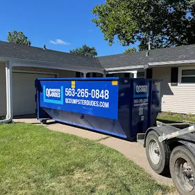 A QC Dumpster Dudes dumpster positioned neatly on a residential driveway, showcasing its utility for home decluttering projects.