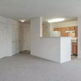 an empty living room and a kitchen with a counter