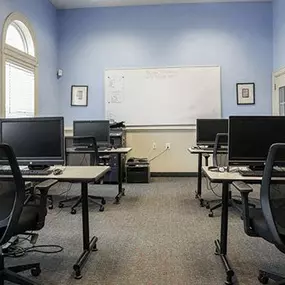 a classroom with computers and desks and a whiteboard