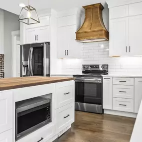 The wood accent hood creates a great focal point and helps bring all the rustic wood tones together in this amazing kitchen design.