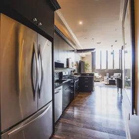 a large kitchen with stainless steel appliances and a wooden floor at The Knights @ 506 Delaware Apartments, Buffalo, 14202