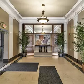 a lobby with potted plants and a large glass door at The Knights @ 506 Delaware Apartments, Buffalo, New York