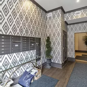 the lobby of a building with mailboxes and a tree in the corner at The Knights @ 506 Delaware Apartments, Buffalo