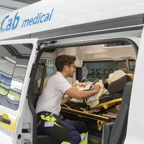 Mitarbeiter easyCab medical betreut Patienten, der auf Stryker liegt im Krankentransportfahrzeug