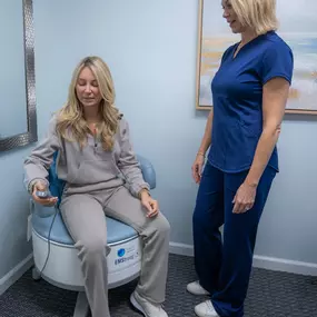 The wellness consultant at Figler Chiropractic and Total Wellness demonstrating the EMStrong machine