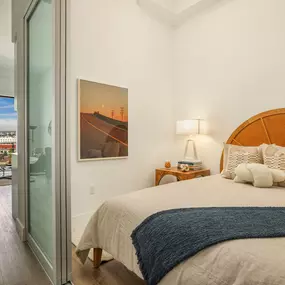 A bedroom with a large bed and a painting of a road with power lines on the wall.