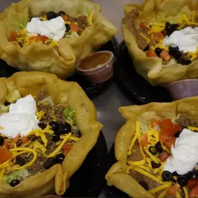 Loaded potato skins topped with sour cream, cheese, and green onions, prepared fresh by Cranberry Hills Eatery & Catering for lunch or catering orders.