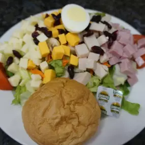 A fresh and colorful Cobb salad featuring greens, hard-boiled eggs, diced ham, and creamy dressing is available for dine-in or catering at Cranberry Hills Eatery & Catering.