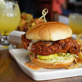 Buttermilk fried chicken, Nashville hot seasoning, lettuce, pickles, and honey butter on a potato bun.