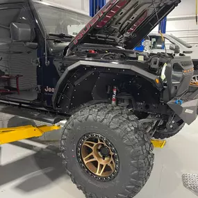 Inside view of Custom Truck Concepts in Hattiesburg, Mississippi, showcasing a customized Jeep being lifted.